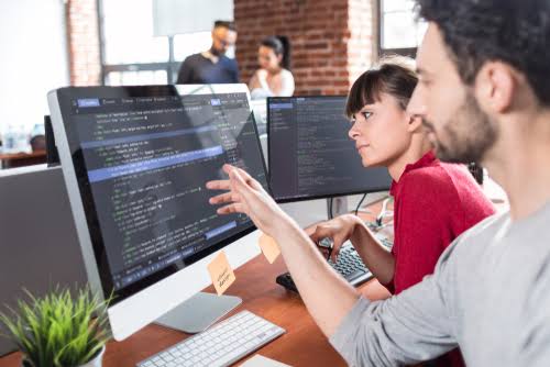 Two engineers reviewing code together at a monitor
